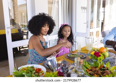 Biracial mother with afro hair eating lunch with daughter at dining table at home. Family, food, drink, unaltered, togetherness, love, childhood, lifestyle and home concept. - Powered by Shutterstock