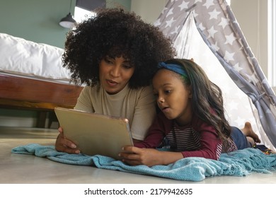 Biracial mother with daughter watching movie over digital tablet while lying in blanket tent at home. Wireless technology, camping, unaltered, family, togetherness, childhood, lifestyle and home. - Powered by Shutterstock