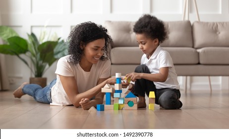 Biracial mother and small cute little son play with colorful toy blocks set building castle enjoy time together, spending weekend in living room modern home with underfloor heating system wooden floor - Powered by Shutterstock