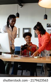 Biracial Photographer Discussing With Multiracial Colleagues In Meeting At Creative Office. Unaltered, Creative Business, Meeting, Teamwork, Diversity, Photography Themes.