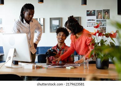 Biracial Photographer Discussing With Multiracial Colleagues In Meeting At Office. Unaltered, Creative Business, Meeting, Teamwork, Diversity, Photography Themes.