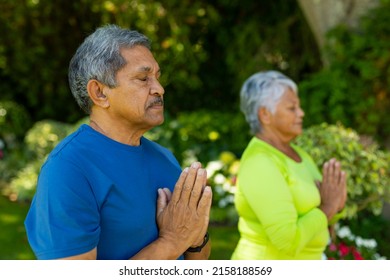 Biracial senior couple with eyes closed meditating in prayer positing while standing in yard. zen, unaltered, love, togetherness, retirement, yoga, fitness and active lifestyle concept. - Powered by Shutterstock