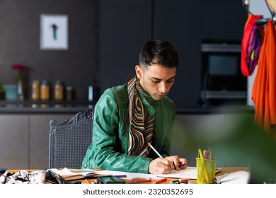Biracial transgender fashion designer sitting at desk and drawing sketches. Gender, fashion, design and lifestyle, unaltered. - Powered by Shutterstock