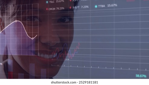 A biracial woman with friendly smile is looking at financial charts on a screen. She has dark hair, brown eyes, and is wearing light makeup - Powered by Shutterstock