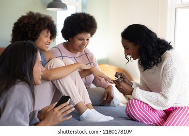 Biracial Young Woman Painting Female's Fingernails While Spending Leisure Time With Friends On Bed. Body Care, Pampering, Beauty Product, Unaltered, Friendship, Togetherness, Lifestyleand Home.