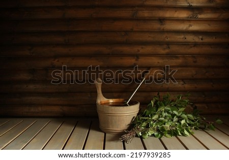 A birch bath whisk (vihta) and a water pail ready for bathers in a Finnish sauna   Room for copy 
