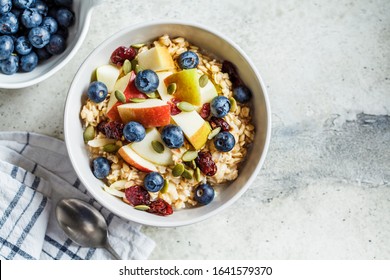 Bircher muesli or overnight oatmeal with apple, banana and blueberries in a gray bowl, copy space. - Shutterstock ID 1641579370