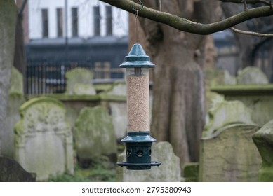 Bird feeder designed to keep squirrels away, set in a peaceful graveyard environment.