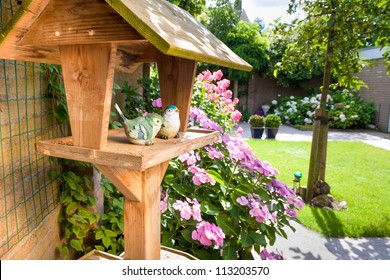 Bird House In Backyard With Two Stone Birds