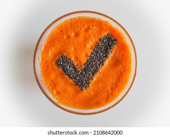 bird view of a glass with healthy cold pressed carrot apple juice and chiaseeds on top in the form of a checkmark for a successfully completed juicing detox fast