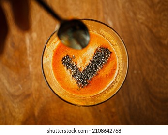 bird view of a glass with healthy cold pressed carrot apple juice and chiaseeds on top in the form of a checkmark for a successfully completed juicing detox fast