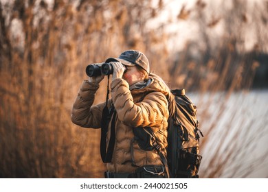 Bird watching. Woman ornithologist with binoculars observes water birds at lake - Powered by Shutterstock