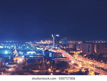 Birds eye view of bright streetlights and traffic at night in city with various high rise buildings