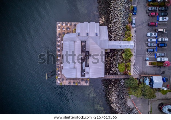Birds eye view of a building built over the Puget\
Sound near a rocky shore.