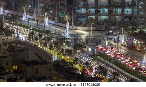 Birds eye view of Dubai skyline timelapse\
and rush hour traffic in downtown at night. Road with palms with\
intersection