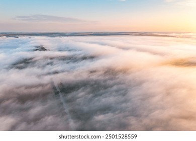 From a bird's eye view, fog is creeping over the valley. Creamy fluffy low clouds cover the ground. Location place Ukraine, Europe. Drone photography. Photo wallpapers. Discovery the beauty of earth. - Powered by Shutterstock