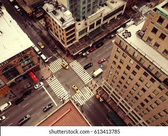 Bird's eye view of New York City. Looking down on Manhattan from skyscraper. Cars, taxis and people moving through busy intersection.  White zebra crossing and New York yellow cabs. Filter effect.