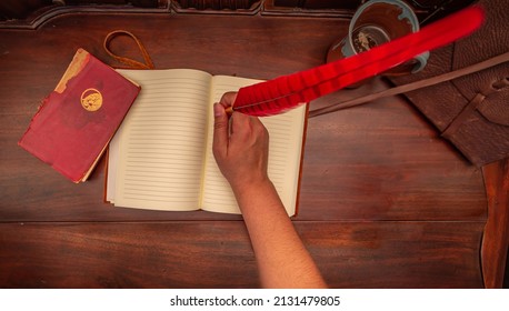 Birds Eye View Of An Open Leather Diary On An Antique Table With A Red Quill Pen And A Coffee Mug Beside A Red Book