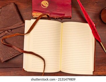 Birds Eye View Of An Open Leather Diary On An Antique Table With A Red Quill Pen And A Coffee Mug Beside A Red Book