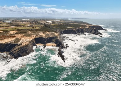 Bird's eye view of the rocky ocean shoreline and lighthouse Cabo Sardao in the distance. Steep cliffs and stormy ocean beneath. Portugal - Powered by Shutterstock