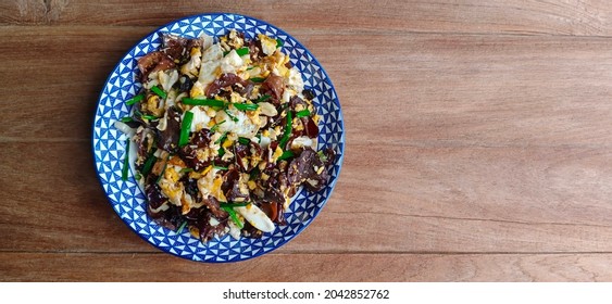 A Bird's Eye View Of Stir Fried Jelly Ear Mushroom With Egg In A Round Dish On A Wooden Table.