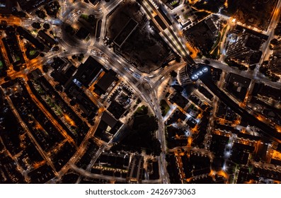 Birds eye view of tall financial and commercial buildings with shadow and cars moving on city street during night with illuminated lights in London city