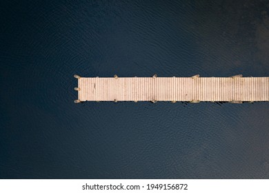 Birds eye view of wooden jetty leading out over lake taken with drone. - Powered by Shutterstock