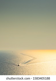 Bird's View Of A Single Motor Boat Leaving A Wake Pattern On The Ocean At Golden Hour 