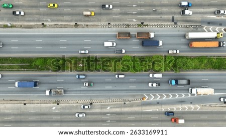 A bird's-eye perspective captures a bustling multi-lane road with cars, a bus, and a motorcyclist, all adhering to marked lanes, illustrating the organized flow of urban traffic.
