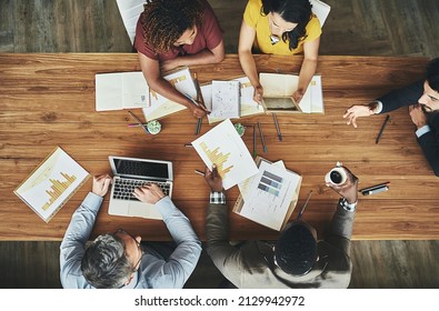 Birds-eye view of business. High angle shot of a team of businesspeople meeting around the boardroom table in the office.