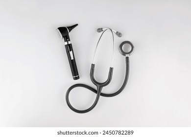 Birds-eye view of essential medical doctor tools, centered and isolated on a white background. Otoscope used for examining inside patients ears and a stethoscope for listening to internal body sounds. - Powered by Shutterstock