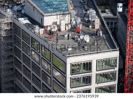 Birdseye view of roofer waterproofing the flat roof of a commercial building.