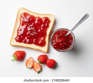 A bird's-eye view of the strawberry jam-filled bread and strawberry fruit on a white background