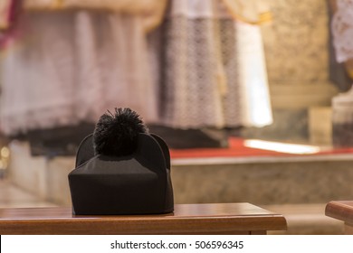 Biretta, a catholic priest's black hat, lying on a chair during a traditional latin mass