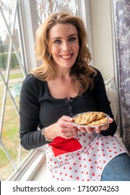 BIRMINGHAM, AL - APRIL 7, 2020: A 37 Year Old Redheaded Woman Holding A Plate Of Fresh Cookies.