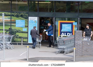 BIRMINGHAM, UK - 2020: Coronavirus Social Distancing With Aldi Supermarket Staff Handing Out Hand Sanitiser To Clean Trolley