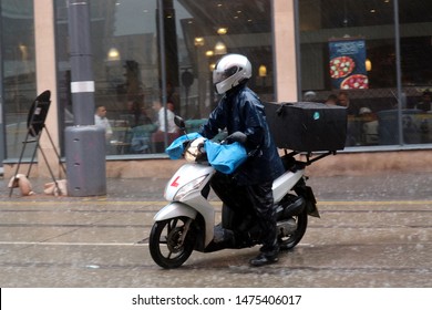 Birmingham, UK - August 6 2019; A Fast Food Deliveroo Delivery Driver On A Scooter In Heavy Rain.