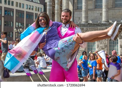 Birmingham, UK - May 25, 2019 - A Man On Stilts Lifts Someone Off Their Feet As People Gathering For The Pride Parade Look On.