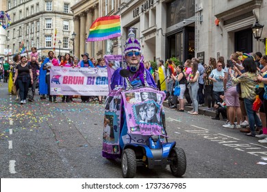 Birmingham, UK - May 25, 2019 - A Man In A Mobility Scooter Wears A  Gown And A Jewelled Crown As He  Pays Homage To Princess Diana. Behind Him Brum Bi Group Carry A Banner In The Pride Procession.