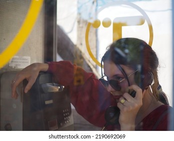 Birmingham, United Kingdom - 08,13,2022: Young Woman In Sunglasses And Red Blouse Using Old British Telecom Pay Phone.