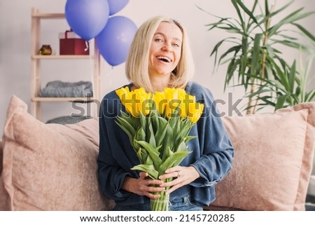 Birthday, 40 years old, happy woman with bouquet of flowers and balloons at living room