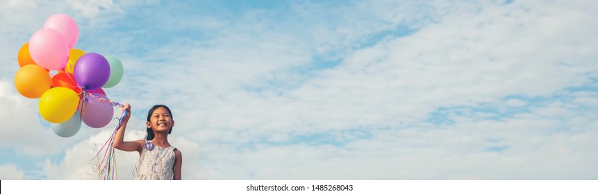 Birthday balloon Holding by Happy child in summer carnival.Colorful of multicolored balloons floating in blue sky banner background with copy space,vintage filter effect.Freedom concept. - Powered by Shutterstock