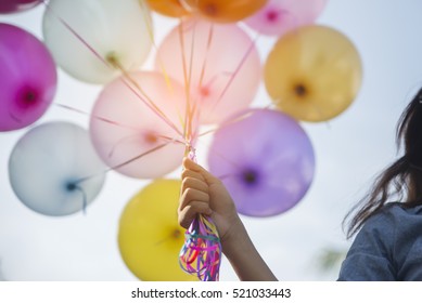 Birthday balloon Holding by Happy woman in summer carnival. Colorful of multicolored balloons floating in Happy New Year Party, vintage filter effect. Freedom, Birthday balloon concept.