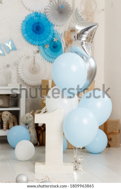 Birthday\
blue decorations - gifts, toys, balloons, garland and figure for\
little baby party on a white wall\
background.