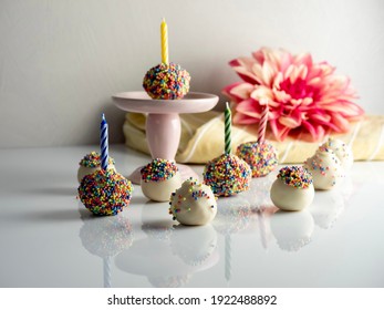 Birthday Cake Balls, Truffle Dessert, Decorated With White Coating And Colorful Sprinkles, Delicious For A Celebration On A White Surface With A High Gloss Reflection.