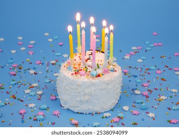 Birthday cake with burning candles on blue background with many colorful sprinkles. - Powered by Shutterstock