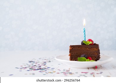 Birthday cake with candle, light blue background, bokeh