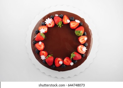 Birthday Cake In Chocolate With Strawberries, Blueberries And Snowflake On White Background. Top View. Picture For A Menu Or A Confectionery Catalog.