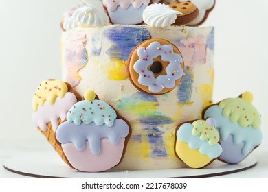 Birthday Cake With Colorful Cream Cheese Frosting Decorated With Cookies. Gingerbread Cookies In The Shape Of Rainbow, Cupcakes, Doughnut And Ice Cream. White Background