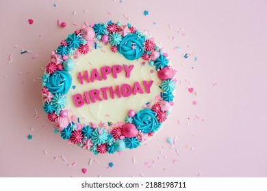 Birthday Cake With Colorful Happy Birthday Greeting And Sprinkles On A Pink Background, Overhead View